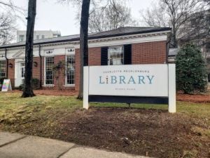 Exterior view of a red brick library building with a sign displaying 'Charlotte Mecklenburg Library'.